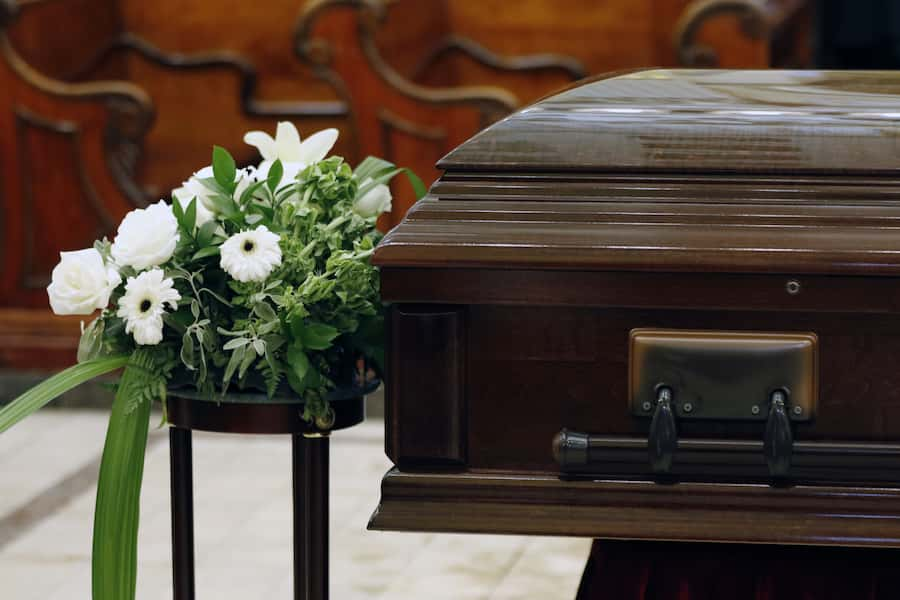 dark wooden coffin with flowers beside