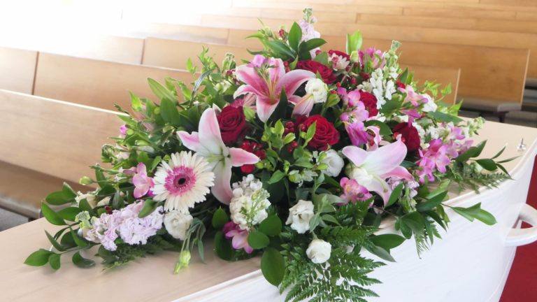 white coffin with pink flowers